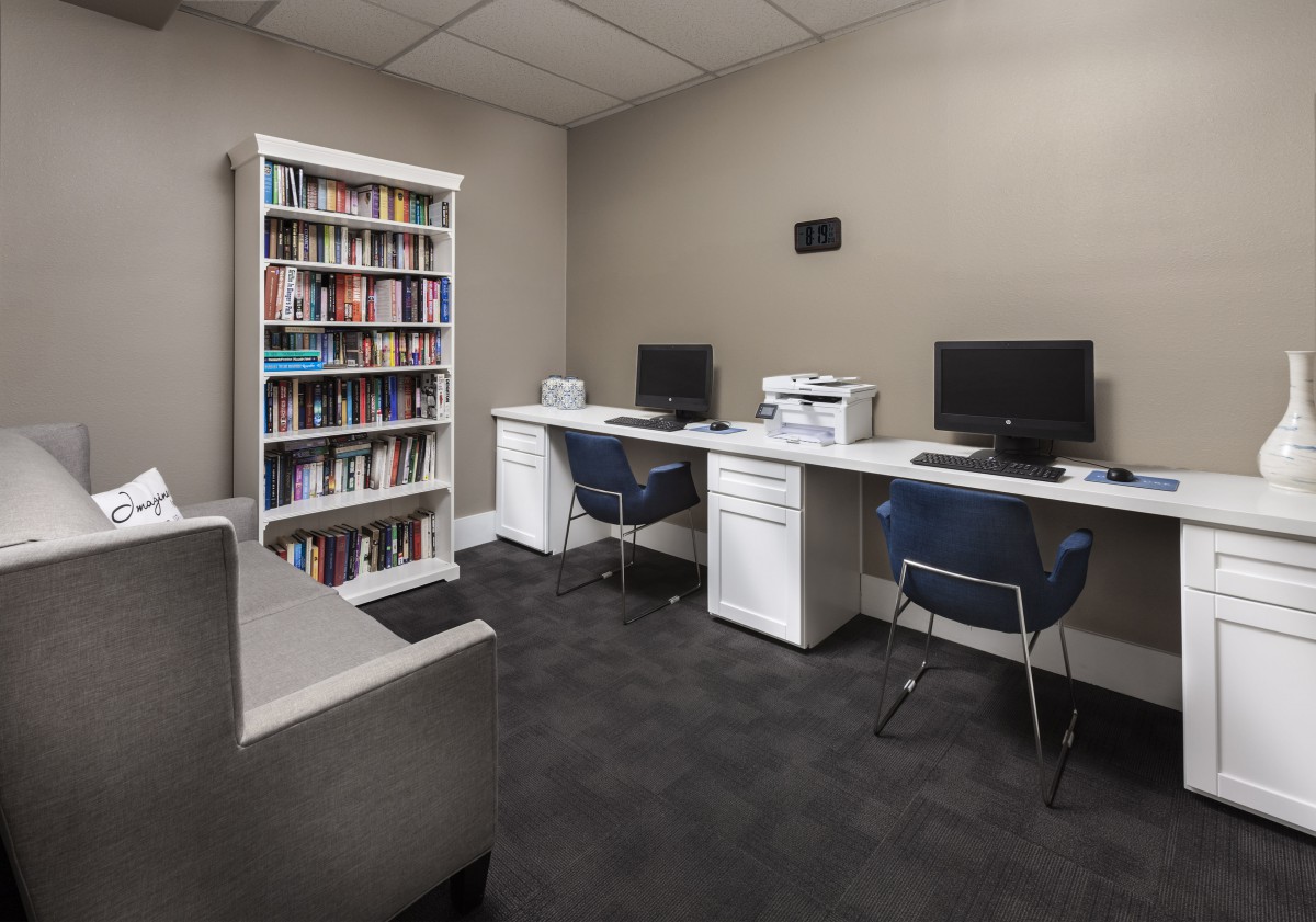A modern office space with two computer workstations, a bookshelf, and a printer.