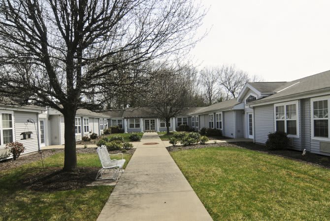 A serene courtyard with a central pathway surrounded by houses and benches.