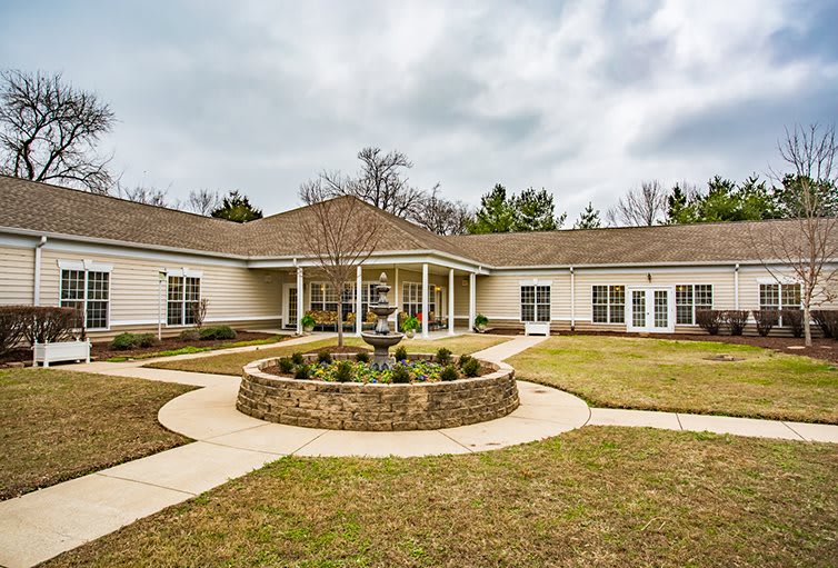 A single-story building with a landscaped roundabout and pathway in front.