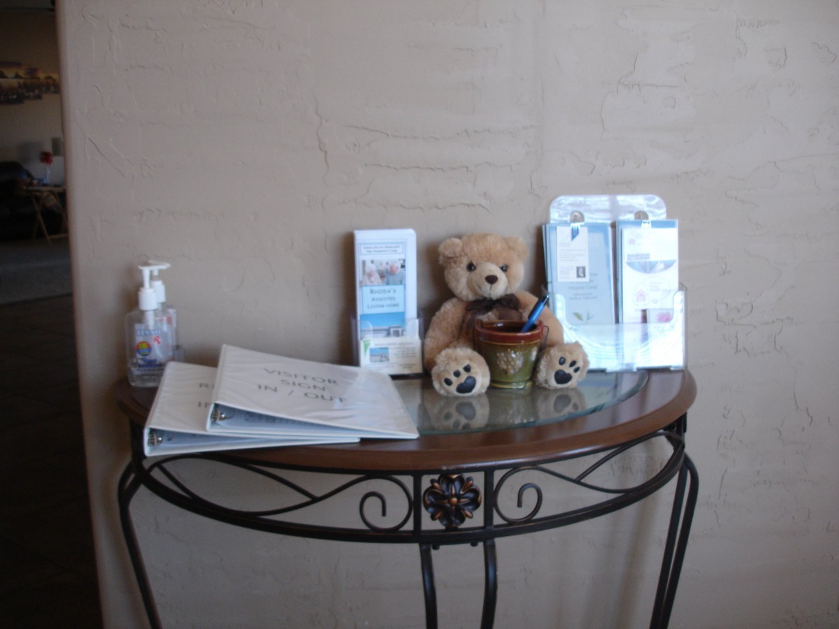 A waiting area setup with brochures, a teddy bear, and hand sanitizer on a decorative table.