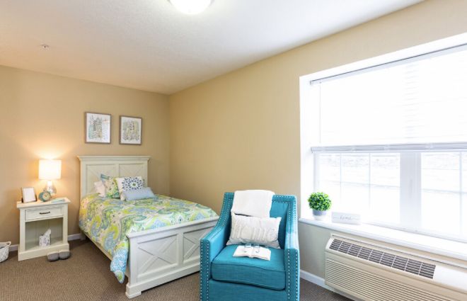 A cozy bedroom with a single bed and an armchair by the window.