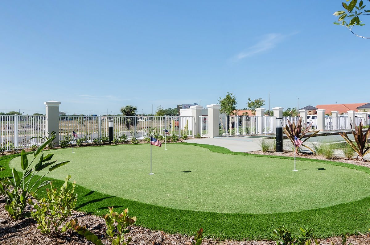 A well-maintained outdoor putting green under a clear blue sky.