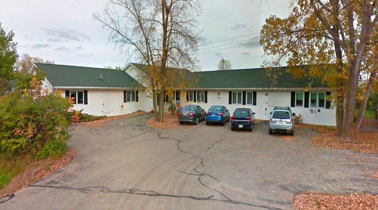A small parking lot in front of a single-story building on an overcast day.