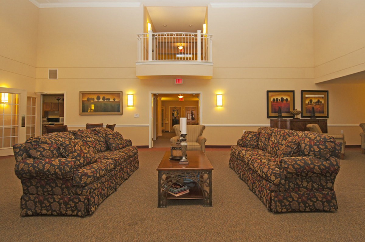 A cozy living room with patterned sofas, a central coffee table, and warm lighting.