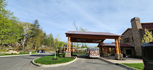 A welcoming entrance with a wooden canopy and a vehicle parked on a sunny day.