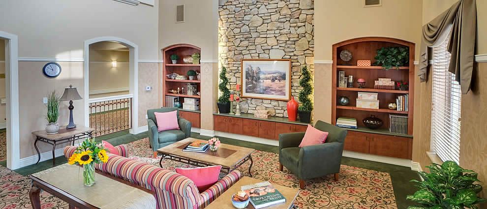 A cozy living room featuring a stone fireplace, comfortable chairs, and tasteful decor.