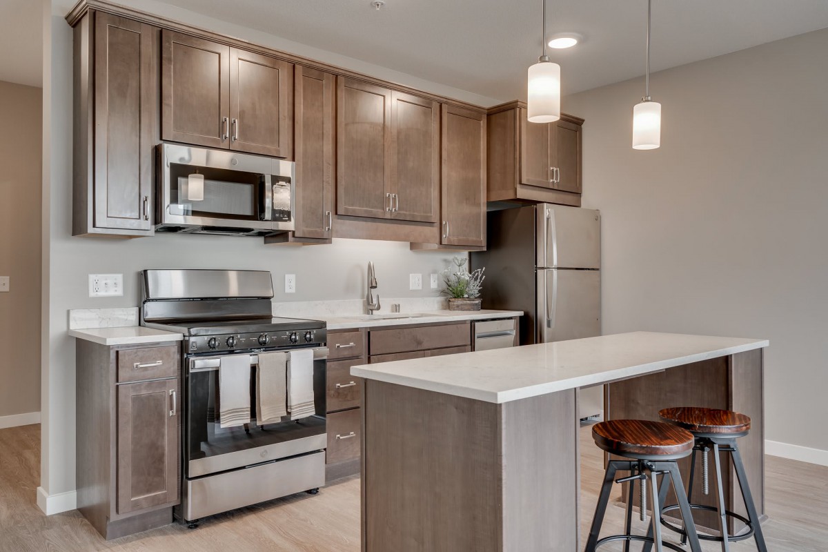 A modern kitchen with stainless steel appliances and a central island with bar stools.