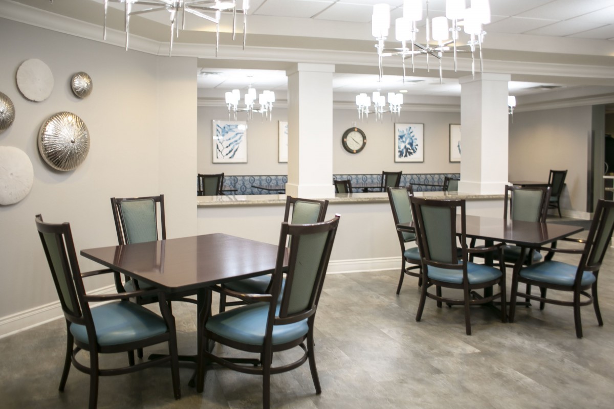 A modern dining area with multiple tables and chairs under elegant chandeliers.