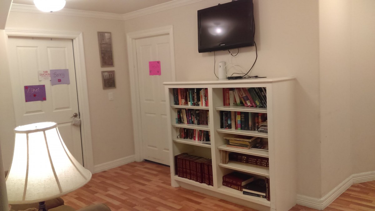 A cozy living room corner with a bookshelf filled with books and a TV mounted on the wall.