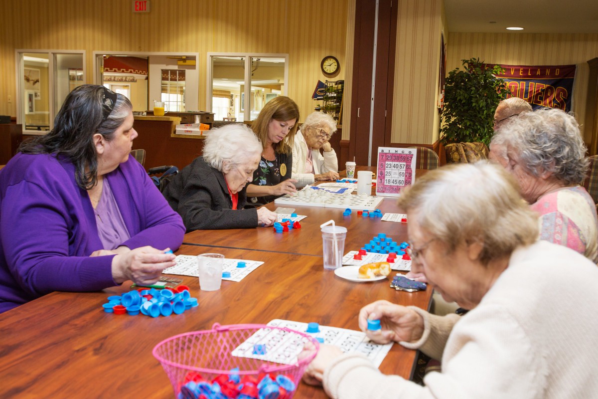 A group of seniors engaged in craft activities at a table indoors.