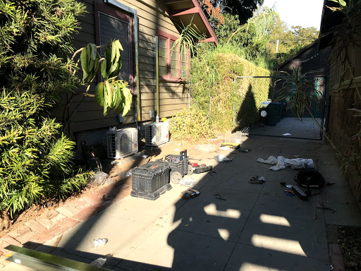 A view of a residential outdoor area with scattered items and lush greenery.