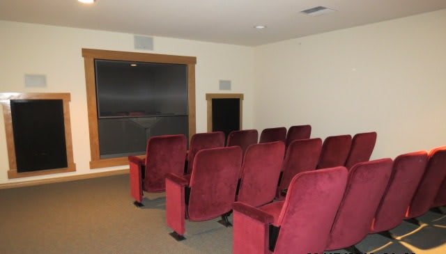A small home theater room with red chairs and a large screen.