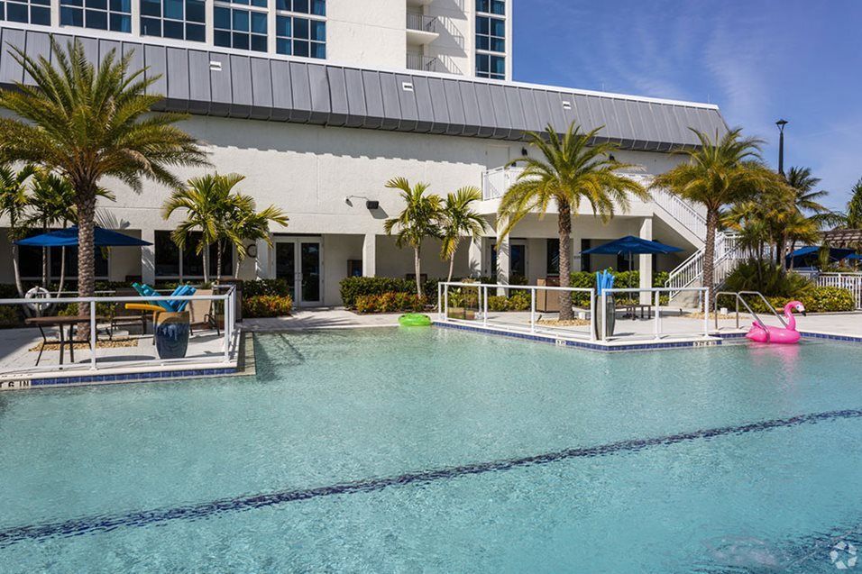 A luxurious outdoor pool area surrounded by palm trees and modern architecture.