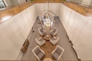 A modern lounge area featuring a circular seating arrangement beneath an elegant chandelier.