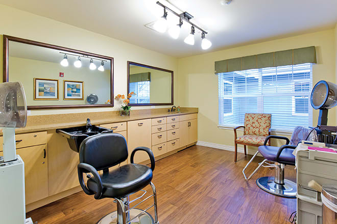 A well-lit hair salon interior with a styling chair, mirror, and sink.