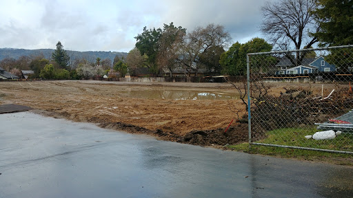 A cleared and fenced plot of land under a cloudy sky, ready for new development.
