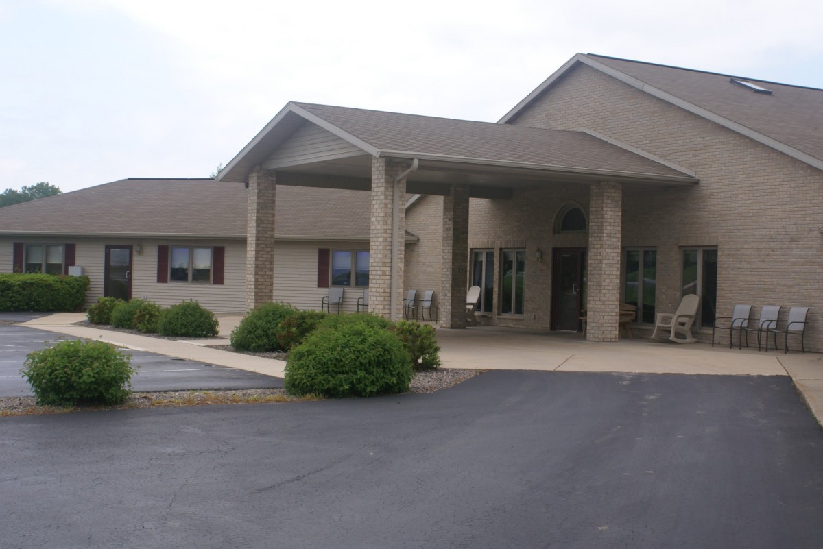 A suburban building with a covered entrance and a parking lot in front.