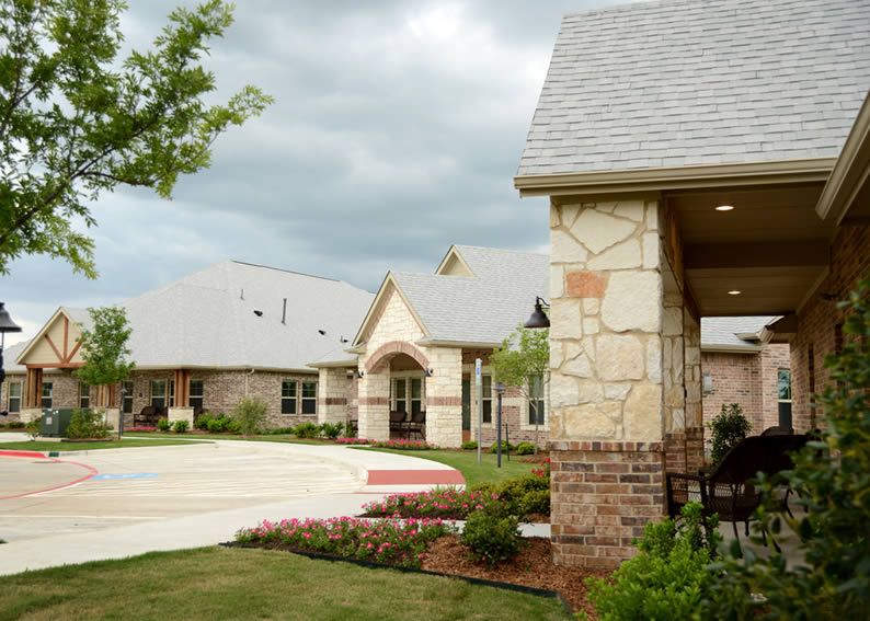 A suburban residential building with stone facades under a cloudy sky.