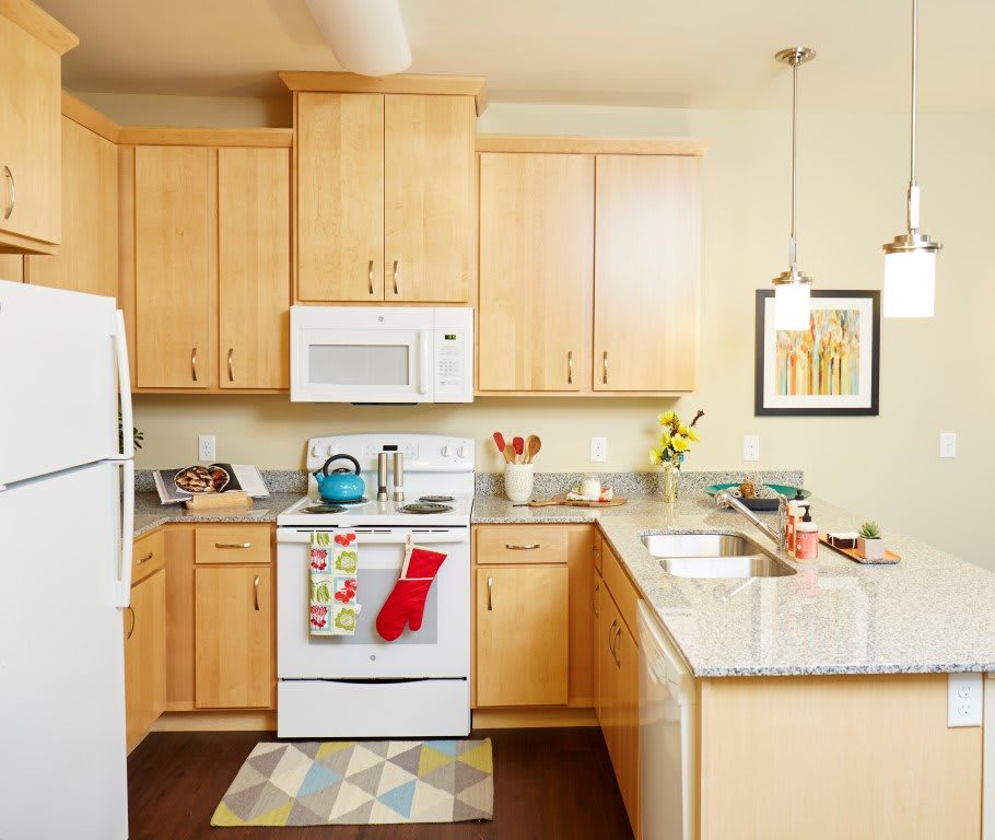 A modern kitchen with wooden cabinets, white appliances, and decorative touches.