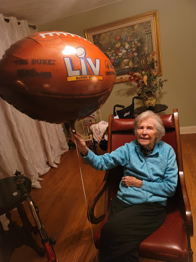 An elderly woman enjoying a festive moment with a football-themed balloon.
