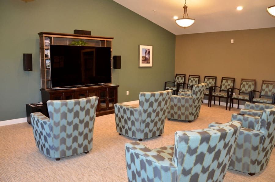 A cozy seating area with patterned chairs facing a large television in a modern living room.