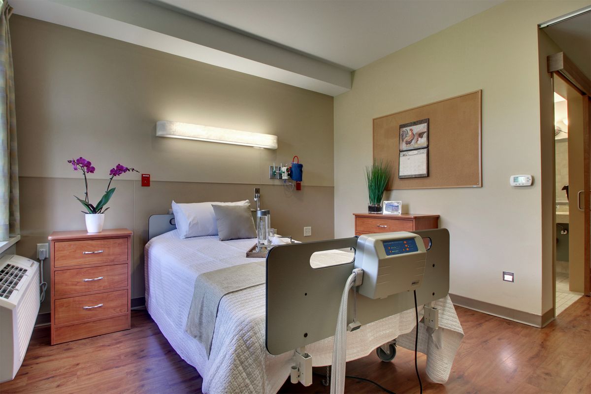 A modern hospital room with a neatly made bed and medical equipment.