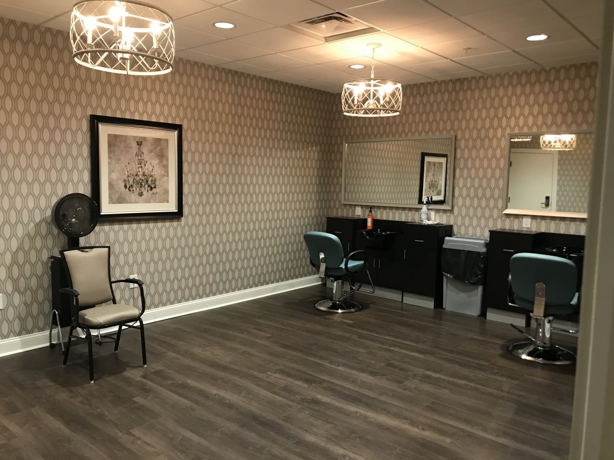 A modern salon interior featuring stylish chairs, large mirrors, and elegant lighting.