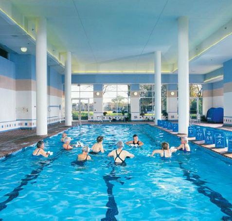A group of people participating in a water aerobics class in an indoor pool.