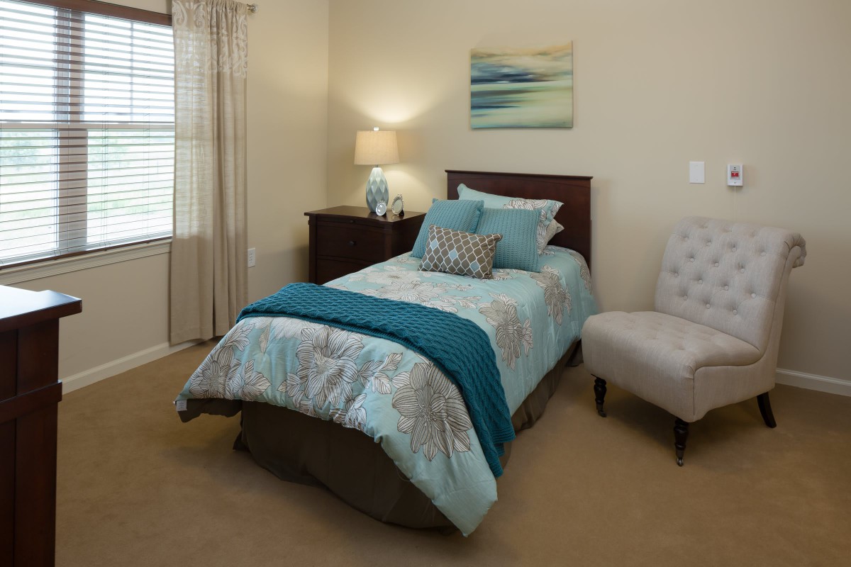 A cozy bedroom with a single bed, decorative bedding, and soft lighting.
