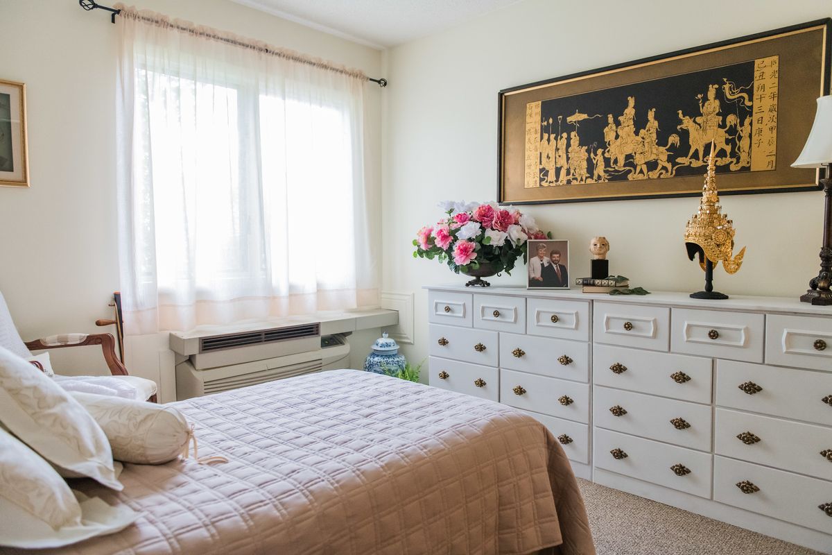 A cozy bedroom with a dresser, floral arrangement, and wall art.