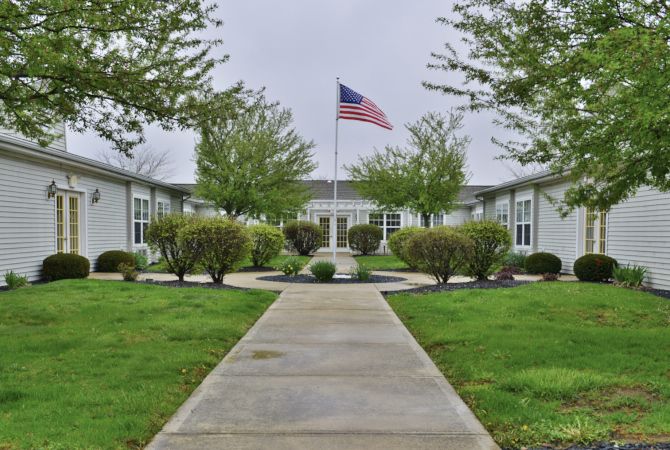 A landscaped courtyard with a central pathway leading to a building, featuring an American flag.