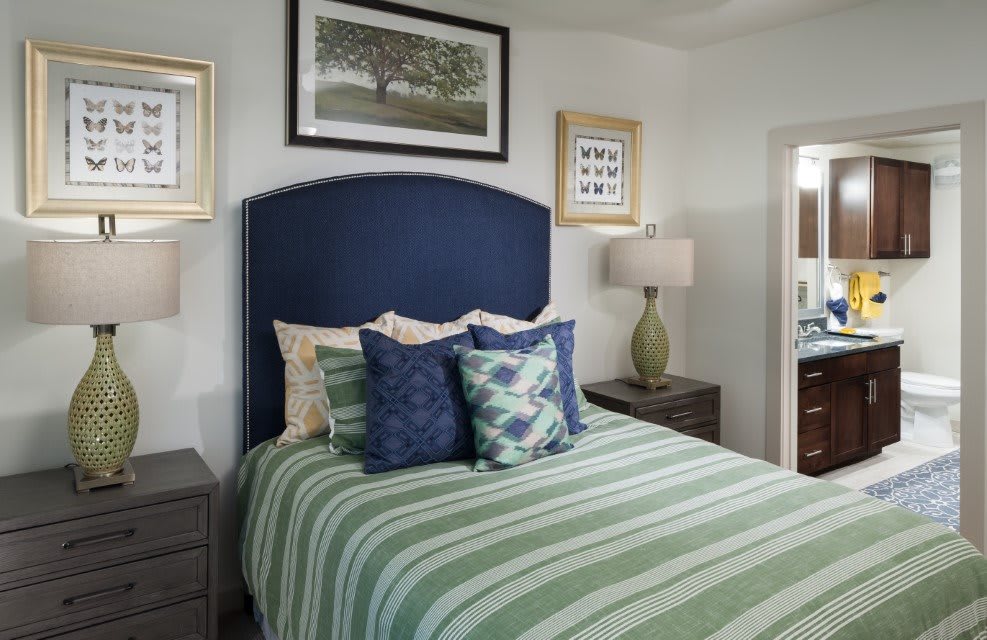 A cozy bedroom featuring a bed with striped bedding, decorative pillows, and framed artwork on the walls.