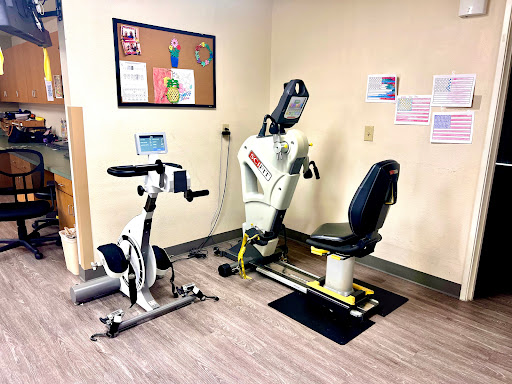 A fitness area featuring a recumbent bike and a seated exercise machine, designed for rehabilitation and low-impact workouts.