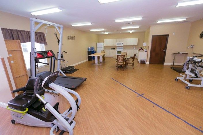 A spacious indoor gym with treadmills and exercise equipment on a wooden floor.