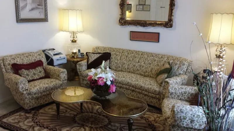 A cozy living room with floral-patterned furniture, a brass coffee table, and a decorative mirror.