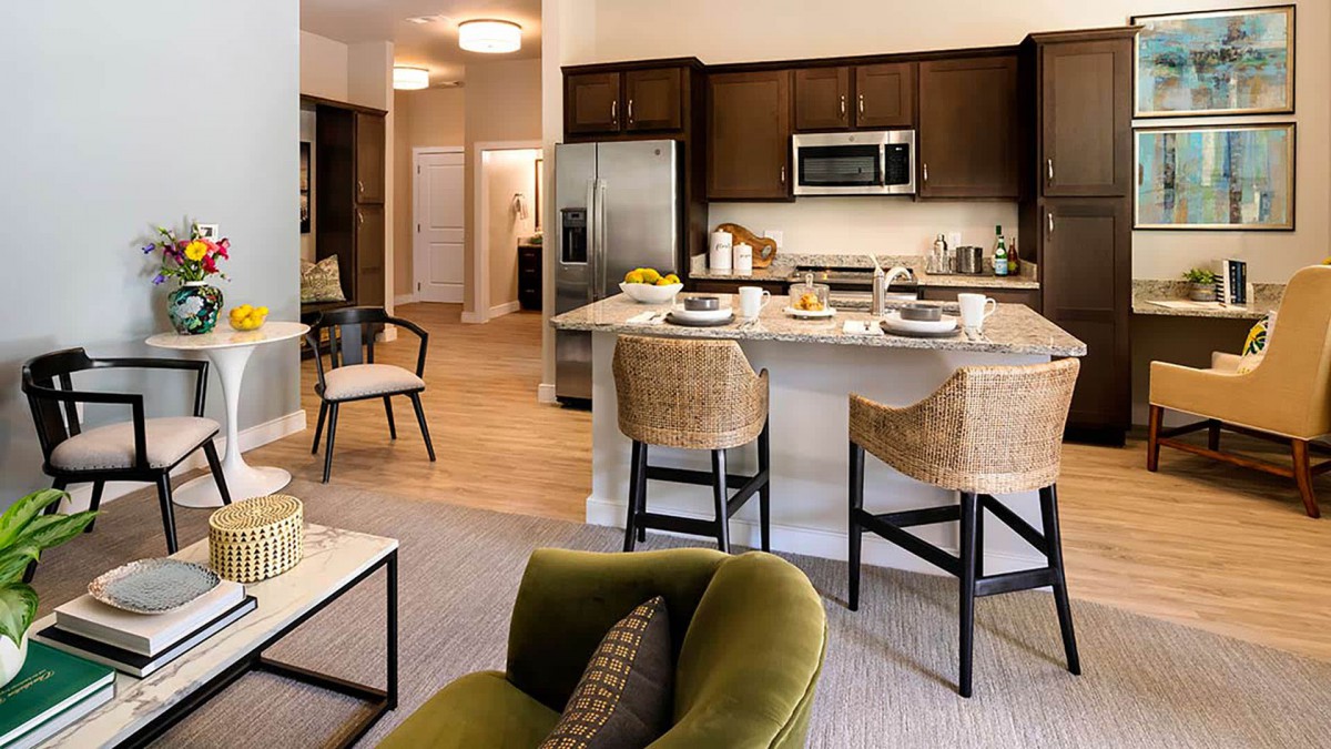 A modern kitchen and living area featuring a spacious layout with bar stools at the counter and contemporary appliances.