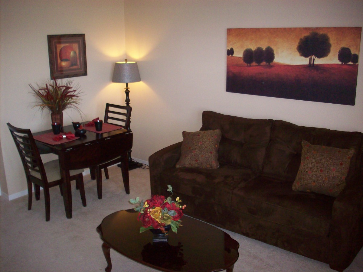 A cozy living room with a sofa, artwork on the wall, and a dining table with elegant decor.