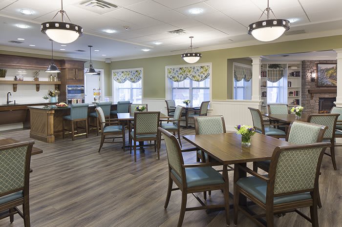 A well-lit dining area with neatly arranged tables and chairs, surrounded by windows.