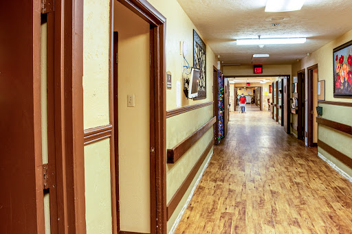 A well-lit hallway with wooden flooring and artwork on the walls.