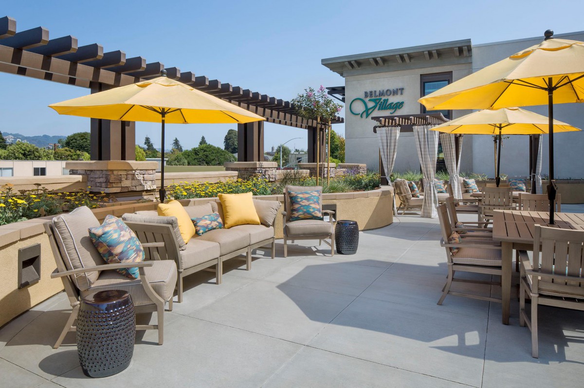 An inviting patio area with comfortable seating and bright yellow umbrellas under a clear sky.