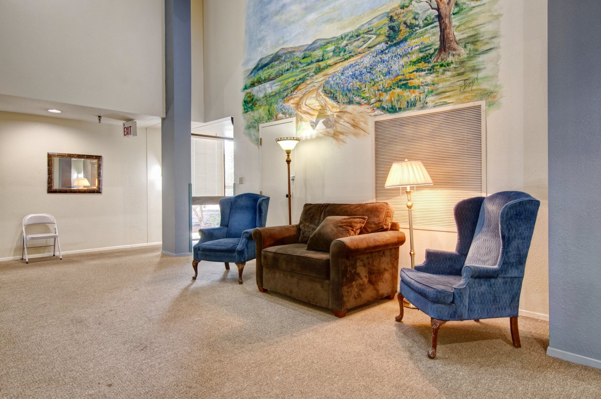 A cozy living room with armchairs and a vibrant mural.