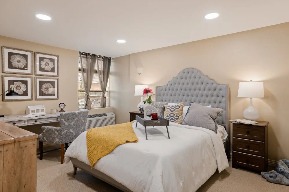 A cozy and well-decorated bedroom with a tufted headboard, stylish bedding, and bedside lamps.