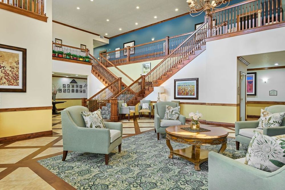 A spacious and elegantly decorated lobby featuring comfortable seating, stylish lighting, and a grand staircase.