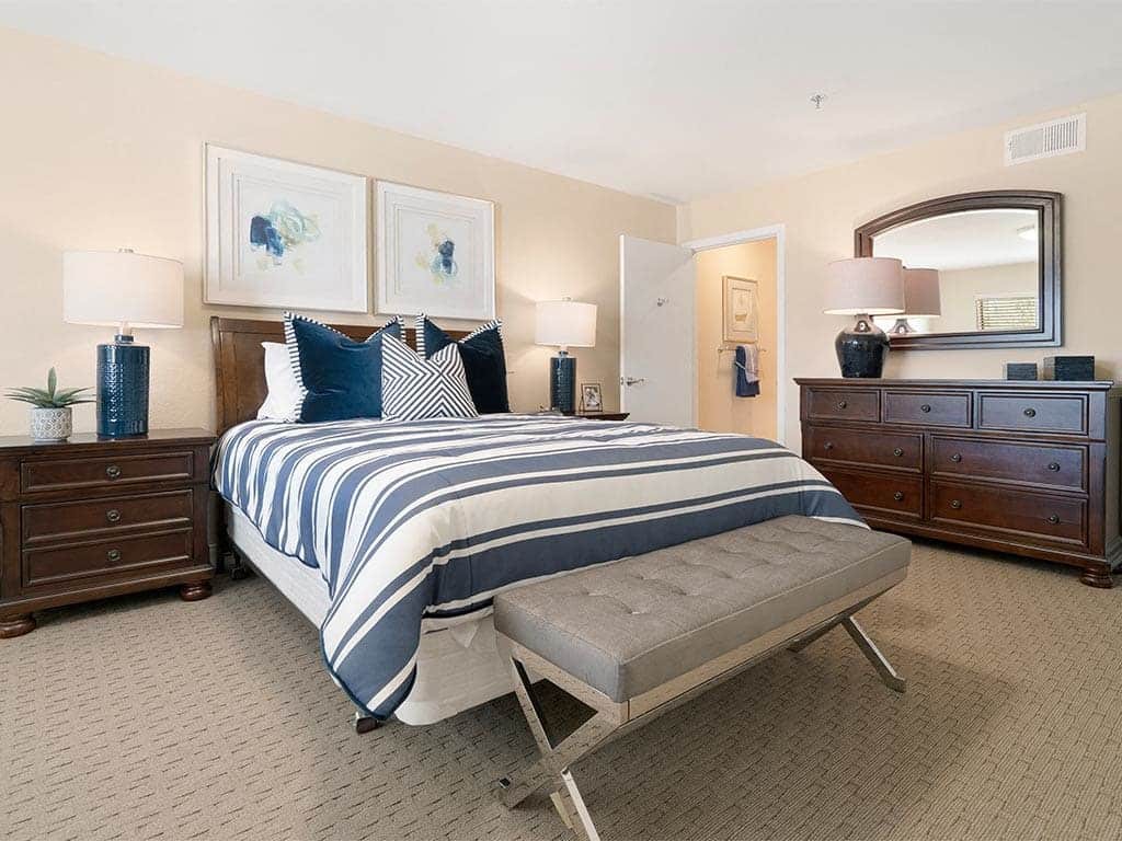 A well-decorated bedroom with a striped bedspread, elegant furniture, and tasteful artwork.