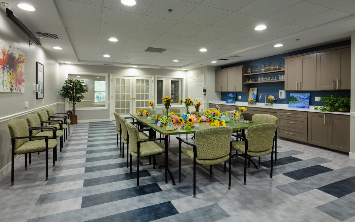 A modern dining room with a long table set for a meal, featuring stylish chairs and a decorative centerpiece.