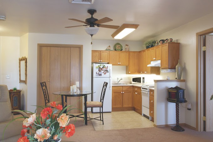 A cozy kitchen with wooden cabinets, a dining area, and a variety of appliances.