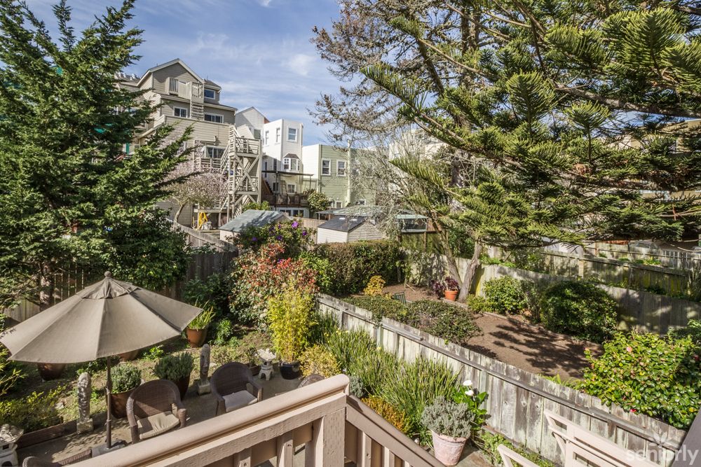 A serene backyard garden with a deck overlooking lush greenery and trees, set in an urban environment.