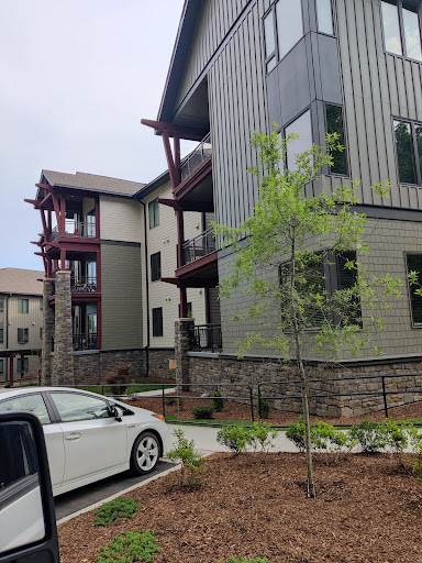 A modern apartment building with a landscaped entrance and a parked vehicle.