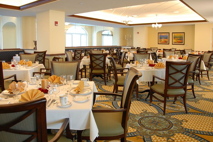 An elegant dining room with neatly arranged tables and chairs, set for a meal.