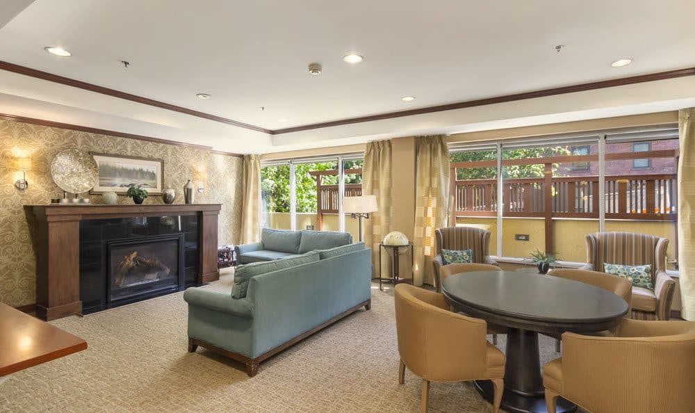 A cozy living room featuring a fireplace, comfortable seating, and large windows with curtains.